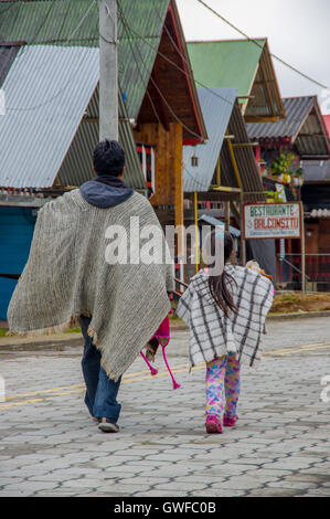 PASTO, Colombia - 3 Luglio 2016: uomo a camminare con una bambina vestito con abiti tradizionali in una piccola località di la cocha lago Foto Stock