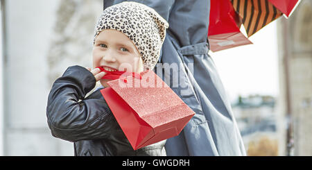 Elegante autunno a Parigi. sorridente giovane madre con bambino e borse per lo shopping nelle vicinanze del Arc de Triomphe a Parigi in Francia a piedi Foto Stock