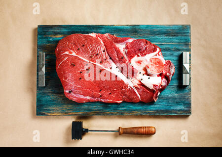 Vista dall'alto di carni fresche bovine Carne di vitello su rustiche vassoio in legno con martello di carne Foto Stock