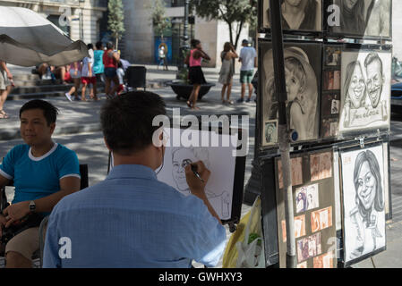 L'artista di strada il disegno di una caricatura di un giovane uomo lungo La Rambla. Esempi di altri suoi lavori appeso accanto a lui. Barcellona. Foto Stock