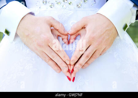 Sposa e lo sposo tenere le mani in amore forma di cuore. Il matrimonio di nozze e concetto di immagine. Foto Stock