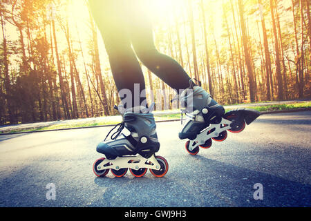 Ragazza adolescente su pattini a rotelle in estate. Pattini a rotelle in linea sport immagine concettuale. Foto Stock