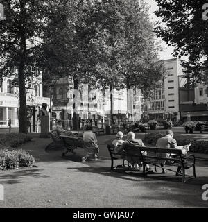 1950s. Una fotografia da J Allan Cash di persone al di fuori seduta sulle panchine di legno nel piccolo parco a Leicester Square nel West End di Londra. Foto Stock