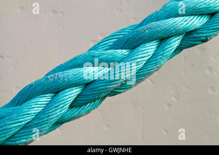 Close up di un blu leggermente avvertire la cima di ormeggio sotto tensione contro uno sfondo bianco Foto Stock