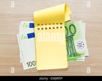 Un centinaio di banconote in euro e giallo vuota il blocco note Foto Stock