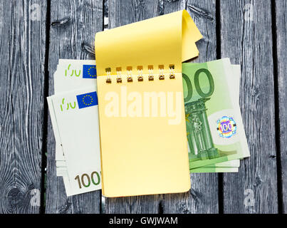 Un centinaio di banconote in euro e giallo vuota il blocco note Foto Stock