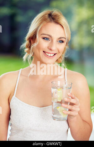Ragazza di bere un bicchiere di acqua ghiacciata al limone Foto Stock