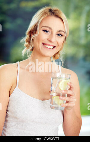 Ragazza di bere un bicchiere di acqua ghiacciata al limone Foto Stock