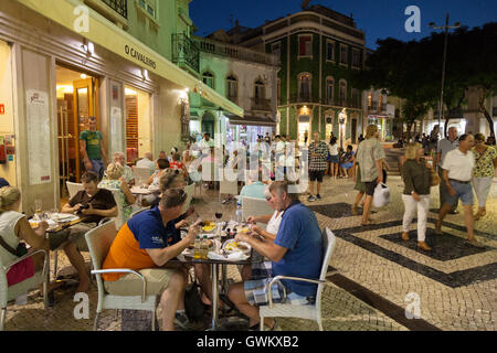 Persone mangiare all'aperto in un ristorante di notte, la città di Lagos, Algarve Portogallo Europa Foto Stock