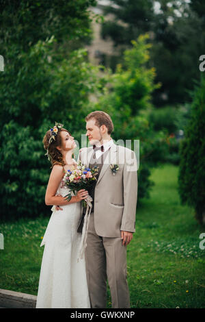 Felice giovane sposa e lo sposo sullo sfondo verde. Foto Stock