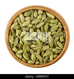 I semi di cardamomo in una ciotola di legno su sfondo bianco. Luce verde elaborato baccelli di Elettaria cardamomum, essiccato semi. Foto Stock