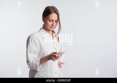 Giovane donna medico tenendo il suo smartphone mentre sorridente nella fotocamera Foto Stock