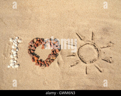 Inquadratura concettuale di I Love Sun come acronimo disposti da conchiglie, rosso ciottoli e disegnati a mano segno di sole sulla spiaggia di sabbia Foto Stock