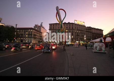 L'ago e filo la scultura da una distanza e traffico in stazione Cadorna di notte, Milano, Italia Foto Stock