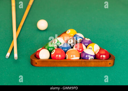 Piscina bastoni cue, una bilia battente e un rack di sfere pronto per un gioco di 8-ball pool. Foto Stock