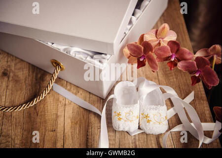 Scatola bianca con un regalo e scarpe per bambini sul tavolo Foto Stock