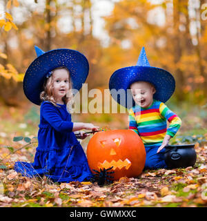 Bambini indossare blu costumi strega con cappelli giocando con zucca e ragno in autunno Park di Halloween. Kids dolcetto o scherzetto. Foto Stock