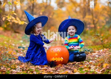 Bambini indossare blu costumi strega con cappelli giocando con zucca e ragno in autunno Park di Halloween. Kids dolcetto o scherzetto. Foto Stock