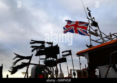 Union Jack flag contrastante con bandiere nere sulla rete da pesca boe / marcatori in porto, Hastings, East Sussex, England, Regno Unito Foto Stock