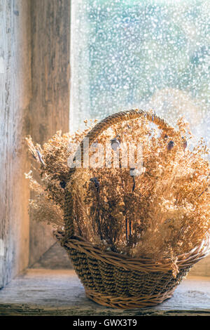 Cestino con fiori secchi sul davanzale di una vecchia finestra in legno Foto Stock