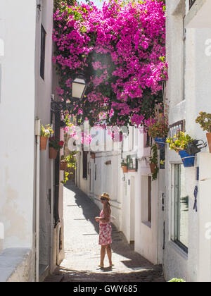 Tourist ammirando il bougainvillea rivestita strada stretta nella città spagnola di Mojacar, Andalusia. Foto Stock