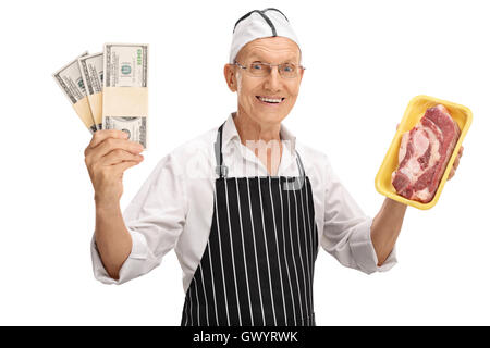 Anziani butcher tenendo una bistecca e pile di denaro isolato su sfondo bianco Foto Stock
