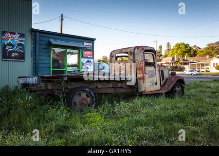 Un vecchio arrugginito carrello, in erba alta, accanto a un auto di seconda mano cantiere Foto Stock