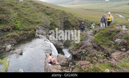La Fata piscine al piede del Black Cuillins vicino Glenbrittle con il nuotatore seduta su roccia Foto Stock