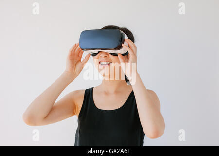 Colpo di felice giovane donna in VR auricolare guardando lontano gli oggetti in realtà virtuale. Femmina con la realtà virtuale ancora gli occhiali di protezione Foto Stock