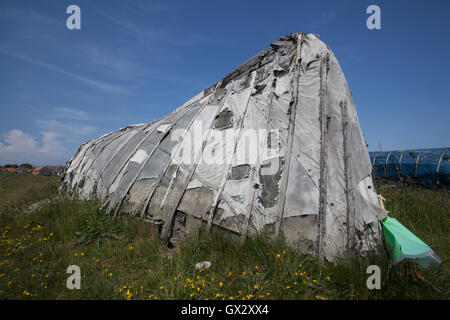 Barca capovolta utilizzato come un capannone sulla spiaggia di Lindisfarne Isola Santa Northumberland England Regno Unito Foto Stock