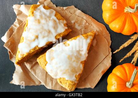 Dolce autunno focaccine di zucca con glassa, vista aerea su ardesia scura sullo sfondo Foto Stock