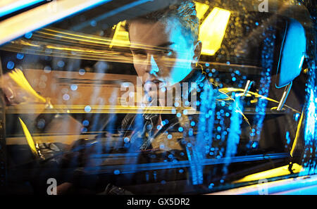 Quadro concettuale di un giovane ragazzo seduto in macchina Foto Stock