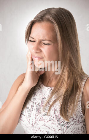 Donna con un mal di denti isolati in grigio Foto Stock