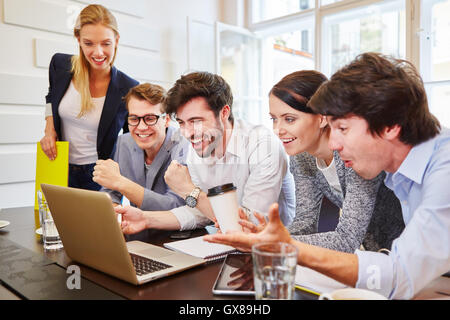 Happy team training con computer e alla ricerca di una soluzione di successo Foto Stock