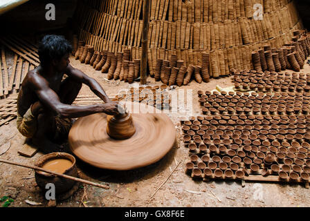 INDIA, nello stato del Jharkhand, Sarwan, villaggio Bhatkundi, piccola scala business, ceramiche, potter rende unidirezionale di tazze di tè da argilla sull'uomo-powered giradischi, le tazze vengono venduti a chai gabbie di plastica prodotti gratuiti Foto Stock