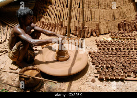 INDIA, nello stato del Jharkhand, Sarwan, villaggio Bhatkundi, piccola scala business, ceramiche, potter rende unidirezionale di tazze di tè da argilla sull'uomo-powered giradischi, le tazze vengono venduti a chai gabbie di plastica prodotti gratuiti Foto Stock