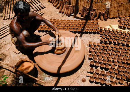 INDIA, nello stato del Jharkhand, Sarwan, villaggio Bhatkundi, piccola scala business, ceramiche, potter rende unidirezionale di tazze di tè da argilla sull'uomo-powered giradischi, le tazze vengono venduti a chai gabbie di plastica prodotti gratuiti Foto Stock