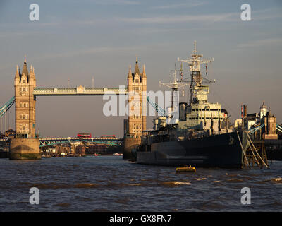 HMS Belfast al suo ormeggio di Londra con il Tower Bridge in background, il fiume Tamigi e Londra Foto Stock