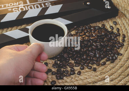 Cattura a mano tazza di caffè caldo con i chicchi di caffè ardesia su una corda di iuta. Foto Stock