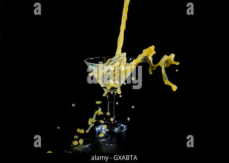 Bicchiere di vino di vetro con succo di colore arancione su sfondo nero Foto Stock