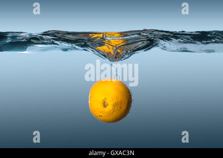 Agrumi tropicali frutta di arancia in acqua su uno sfondo blu Foto Stock