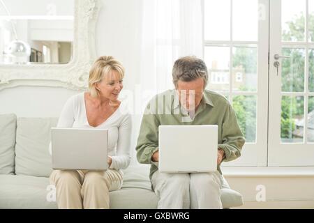 Matura sul divano utilizzando computer portatili Foto Stock