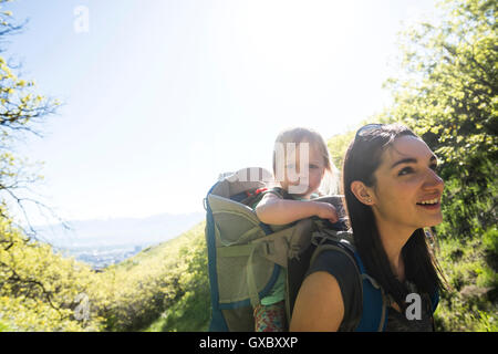 Madre che trasportano giovane figlia, escursionismo la Bonneville litorale Trail nel Wasatch pedemontana al di sopra di Salt Lake City, Utah, Stati Uniti d'America Foto Stock