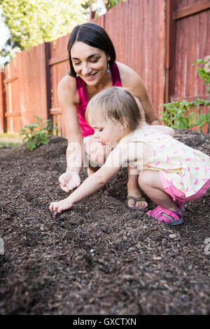 Madre e figlia giovane piantare i semi in giardino Foto Stock