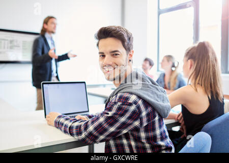 Ritratto di giovane maschio studente utilizzando laptop nell istruzione superiore college classroom Foto Stock