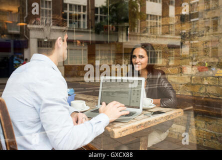 La visualizzazione della finestra di imprenditore e la donna lavora in cafe, London, Regno Unito Foto Stock