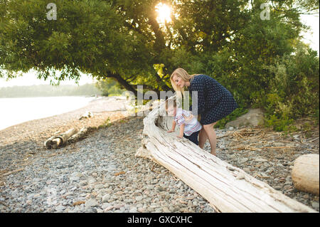 Ragazzo con la madre salendo sul tronco di albero sul Lago Ontario, Oshawa, Canada Foto Stock