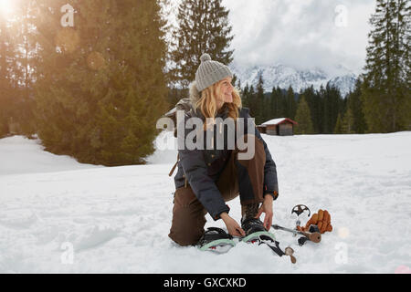 Donna matura la messa con le racchette da neve nel paesaggio innevato, Elmau, Baviera, Germania Foto Stock