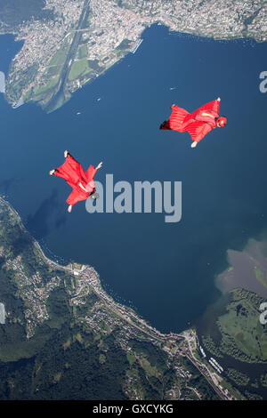 Due wingsuit paracadutista piloti team training e battenti vicino insieme sul lago, Locarno, Ticino, Svizzera Foto Stock