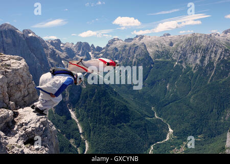 BASE jumping wingsuit piloti stanno saltando insieme da una scogliera e giù per la valle, Alpi Italiane, Alleghe, Belluno, Italia Foto Stock